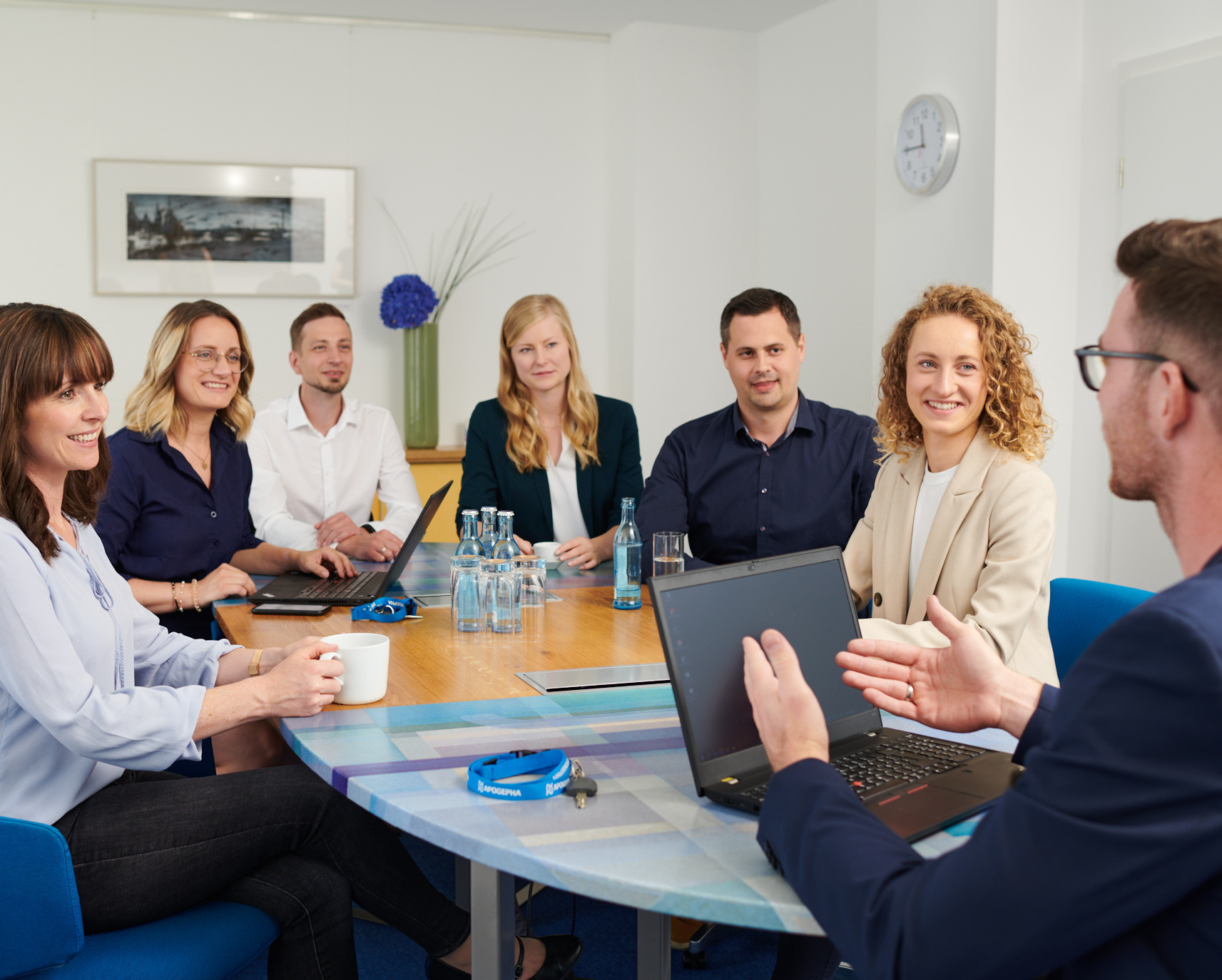 Die Atmosphäre ist freundlich und kooperativ, während die Teammitglieder aktiv an einem Meeting teilnehmen und Ideen austauschen.